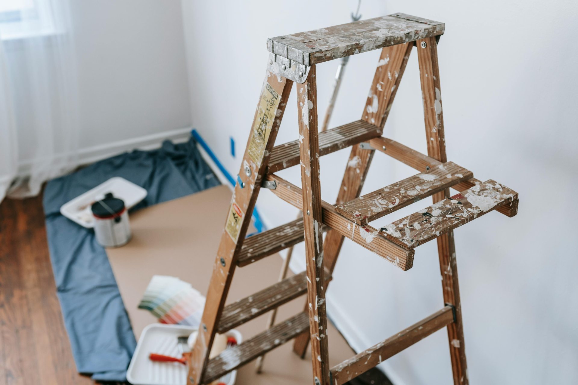 A messy stepladder and painting tools set up for a home interior renovation project.